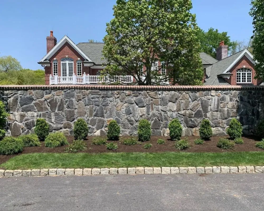Stone wall landscaping in front of brick house